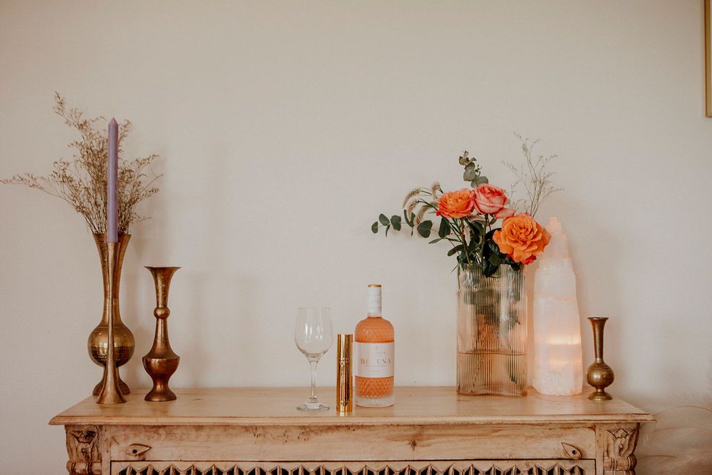 Yoni Elixir on a dresser with roses, a candle and a salt lamp